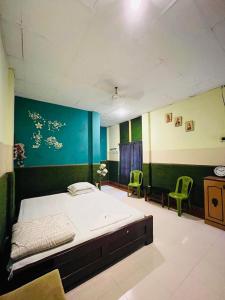 - une chambre avec un lit et deux chaises vertes dans l'établissement Resort Green Earth, à Tajpur