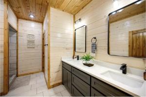 une salle de bain avec un lavabo, une baignoire et un miroir dans l'établissement Whispering Winds, Luxury Cabins, Sleeps 22, à Broken Bow 48 autres photos