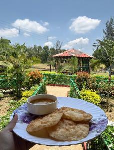 une personne tenant une assiette avec une tasse de soupe et du pain dans l'établissement Resort Green Earth, à Tajpur