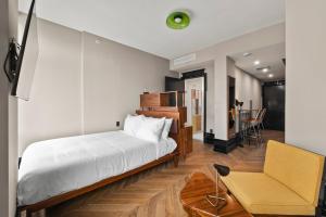 ein Schlafzimmer mit einem Bett, einem Stuhl und einem Tisch in der Unterkunft Freeman 901 by Rove Studio with Shared Amenities in New York