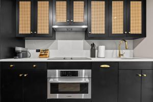 eine Küche mit schwarzen Schränken und einem Edelstahlofen in der Unterkunft Freeman 901 by Rove Studio with Shared Amenities in New York