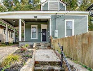 ein grünes Haus mit einem Zaun davor in der Unterkunft Modern Park Avenue Cottage in Hot Springs in Hot Springs