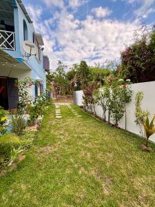 ein Hof neben einem Haus mit einem Zaun in der Unterkunft Maison avec jardin à Grand Gaube a 1 min de la plage in Grand-Gaube