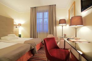 ein Hotelzimmer mit zwei Betten und einem roten Stuhl in der Unterkunft Hotel Branicki in Białystok