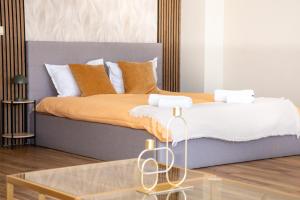 ein Bett mit orangefarbenen und weißen Kissen und einem Glastisch in der Unterkunft !!!1min From The Lift I Luxury Studio In Pirin Palace in Bansko