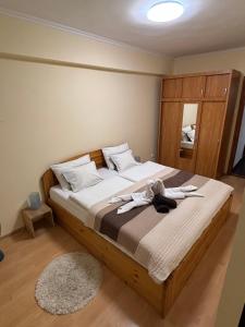 ein Schlafzimmer mit einem großen Bett mit Holzrahmen in der Unterkunft Zenora Apartman in Makó