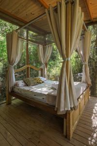 Schlafzimmer mit Himmelbett und Vorhängen in der Unterkunft Casa de Vidro 2, há 90km de São Paulo, com Lago, Piscina, Caiaque, Stand UP, Cascata e Escorrega no Lago - Quinta do Vale Itatiba in Itatiba