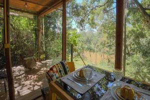 ein Esstisch in einem Zimmer mit Blick auf den Wald in der Unterkunft Casa de Vidro 2, há 90km de São Paulo, com Lago, Piscina, Caiaque, Stand UP, Cascata e Escorrega no Lago - Quinta do Vale Itatiba in Itatiba