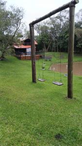 ein Park mit Schaukeln im Gras neben einem Gebäude in der Unterkunft Pousada Caminho do Lago in Rio Rufino