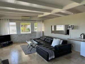 ein Wohnzimmer mit einer schwarzen Couch und einem Fernseher in der Unterkunft Southern Cross Guesthouse in Somerset West