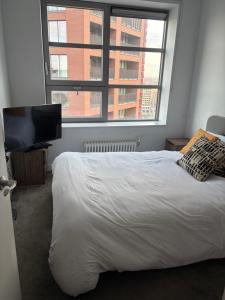 um quarto com uma cama branca e uma janela grande em Cozy and Spacious Central London Stay in Canary Wharf with a City View & a Private Bathroom for Luxury Comfort at a Great Value em Londres