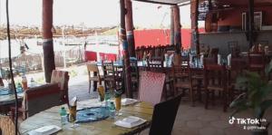 ein Restaurant mit einem Tisch und Stühlen sowie Tischen und Stühlen in der Unterkunft Auberge Cœur Océan in Joal-Fadiout