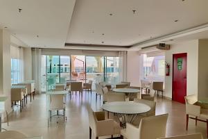 a dining room with tables and chairs and windows at Saint Moritz, bom gosto e estilo in Brasilia