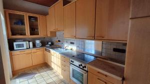 une cuisine avec des armoires en bois et un four à plaques de cuisson dans l'établissement Ferienwohnung im Grünen, à Willebadessen