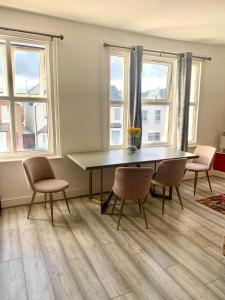 ein Esszimmer mit Tisch und Stühlen und Fenstern in der Unterkunft home from home 2 bed flat in Kingston upon Thames