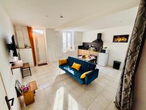 a living room with a blue couch and a kitchen at Le Maréchal Chic - Centre ville - Rive de Gier in Rive-de-Gier