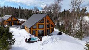a log cabin in the snow with a car in front at Chalets BSL in Saint-Simon-de-Rimouski