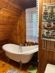 a bathroom with a tub in a room with wooden walls at Magiczny Dom nad Bugiem 