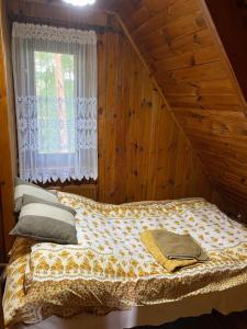 a bed in a wooden room with a window at Magiczny Dom nad Bugiem 