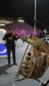 Ein Mann spielt Geige neben einer Frau auf einer Schaukel in der Unterkunft شاليه منتجع جوري حتا الخاص -J3- Jory Hatta Private Resort Chalet in Hatta + 79 Fotos