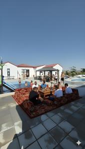 Eine Gruppe von Menschen sitzt auf einem Teppich in der Nähe eines Pools. in der Unterkunft شاليه منتجع جوري حتا الخاص -J3- Jory Hatta Private Resort Chalet in Hatta