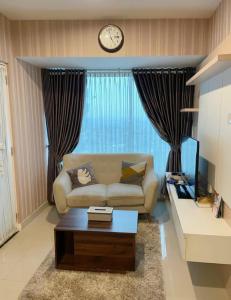 ein Wohnzimmer mit einer Couch und einer Uhr an der Wand in der Unterkunft Indra Homs 