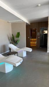 une chambre avec deux chaises blanches et une plante dans l'établissement Increíble Dpto en Costa del Este con vista al mar, à Costa del Este 22 autres photos