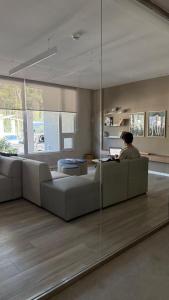 un homme assis sur un canapé dans un salon dans l'établissement Increíble Dpto en Costa del Este con vista al mar, à Costa del Este