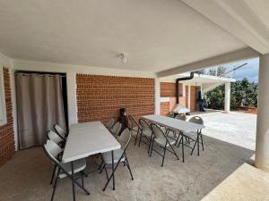 eine Terrasse mit weißen Tischen und Stühlen und einer Backsteinmauer in der Unterkunft Cabañas Aruba in Zacatlán