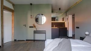Cet appartement comprend une chambre avec un lit et un miroir ainsi qu'une cuisine. dans l'établissement Apartamenty Old House Casino Koszarowa 1, à Wrocław