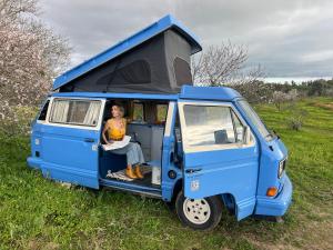 una mujer sentada en la parte trasera de una furgoneta azul en rent a campervan vw t3 azul in Algarve Portugal, en Bicas