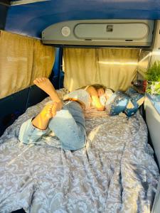 Una mujer acostada sobre una cama en rent a campervan vw t3 azul in Algarve Portugal, en Bicas