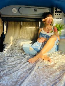 Una mujer sentada en una cama en una autocaravana. en rent a campervan vw t3 azul in Algarve Portugal, en Bicas 23 fotos más