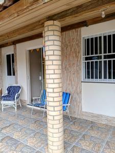 un porche avec deux chaises bleues et une colonne en briques dans l'établissement Recanto Aurora de Bombinhas, à Bombinhas