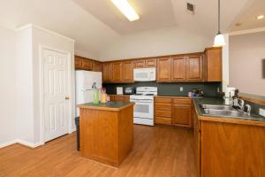 a kitchen with wooden cabinets and a white refrigerator at Near UNT - Downtown Denton - Full Fenced Backyard in Denton