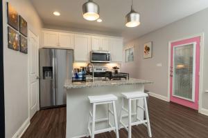 a kitchen with a counter with stools and a refrigerator at Fenced Backyard - Walk to Old Town Lewisville in Lewisville