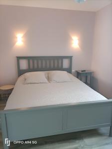a bed in a bedroom with two lights on the wall at Le gîte du Coche avec vue sur la Marne in Damery