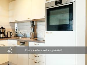 a kitchen with white cabinets and a microwave at Ferienwohnung mit Nordseeblick! de Swolk in Dorum Neufeld