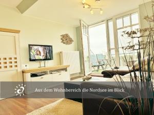 a living room with a tv and a large window at Ferienwohnung mit Nordseeblick! de Swolk in Dorum Neufeld