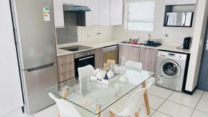 a kitchen with a glass table and white chairs at Luxury Fourways Apartment, Pool, Gym and 24hr Security - Ventura Estate in Sandton