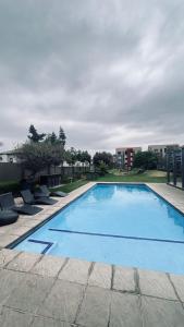 a large swimming pool with chairs around it at Luxury Fourways Apartment, Pool, Gym and 24hr Security - Ventura Estate in Sandton +13 photos