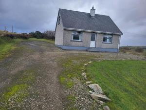 a small house on a hill with a dirt road at Ard A Mhaoire in Glendorragha