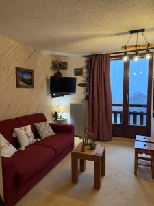 - un salon avec un canapé rouge et une grande fenêtre dans l'établissement Montagne, à Risoul