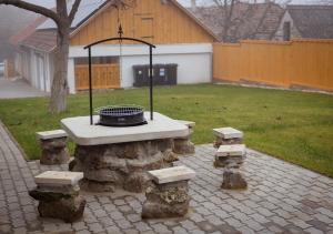 a stone picnic table with benches and a grill at Lebujos Vendégház in Boldogkőváralja