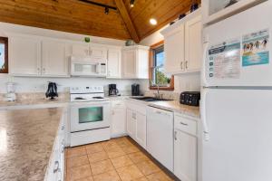 eine weiße Küche mit weißen Geräten und einer Holzdecke in der Unterkunft 1100 - La Maison De Geezer in Corolla