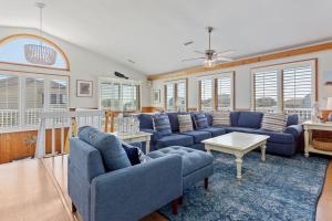 ein Wohnzimmer mit blauen Sofas und einem Tisch in der Unterkunft 1030 - La Ballena Cottage in Corolla