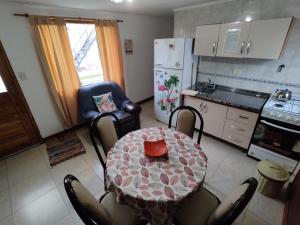 eine Küche mit Tisch und Stühlen und eine Küche mit Kühlschrank in der Unterkunft Acol cabañas 1 y 2 in Perito Moreno