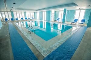 a large swimming pool with blue chairs in a building at Azoris Faial Garden – Resort Hotel in Horta