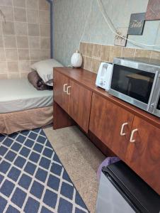 Zimmer mit einer Mikrowelle auf einer Kommode mit einem Bett in der Unterkunft Tight budget room for rent in my singlehouse in Estevan