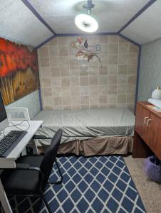 ein Schlafzimmer mit einem Bett und einem Schreibtisch mit einem Laptop in der Unterkunft Tight budget room for rent in my singlehouse in Estevan